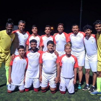 The Indian Blind Football Team stand in two rows for a team photo, with blind outfield players in the centre, one sighted goalkeepers at each end and coach Sunil J Mathew