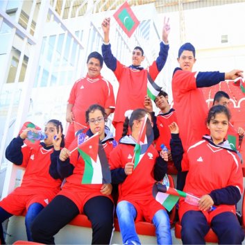 Photo of young players with disabilities sat together with flags from Palestine